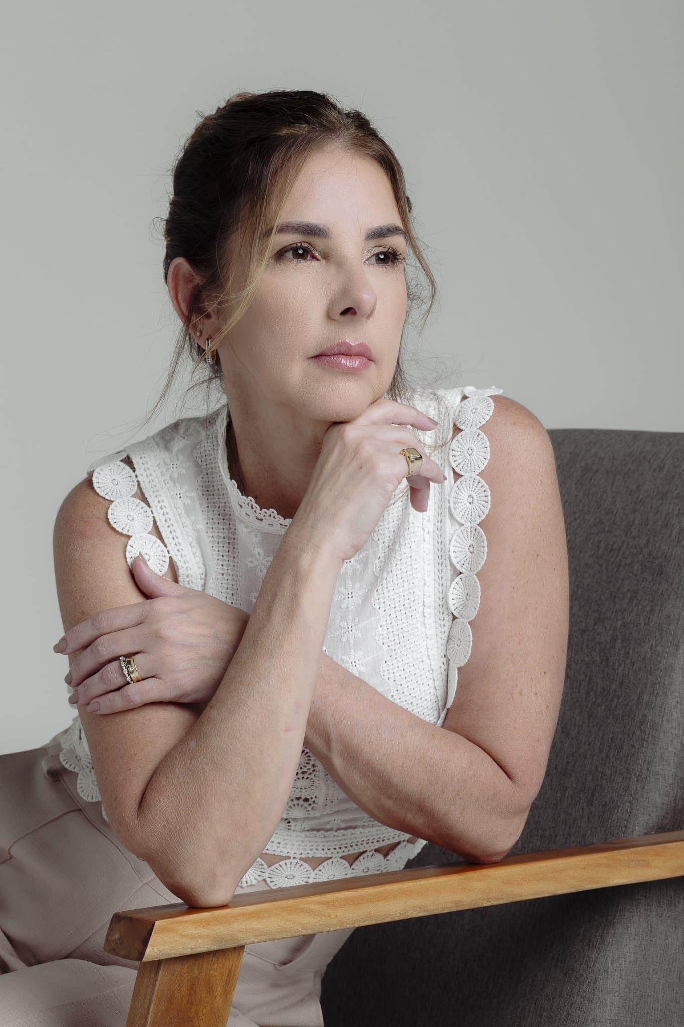 Anna Braga pensativa, com a mão no queixo.